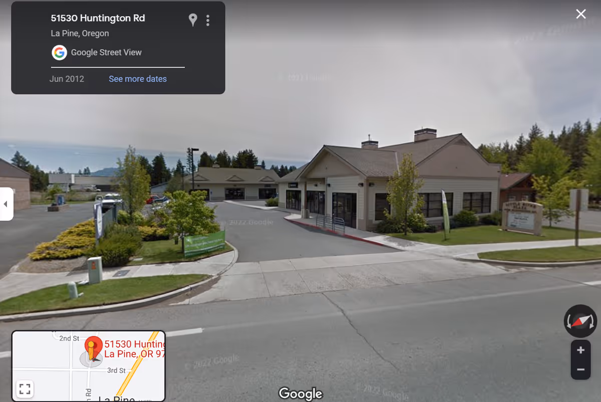 Exterior view of a single-story senior living facility with entrance and surrounding landscaping.