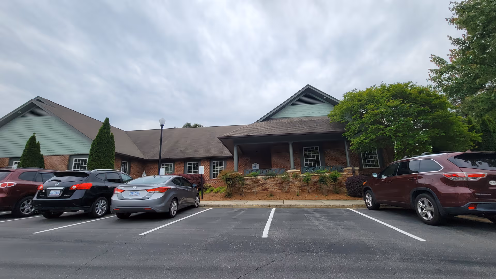 Front view of Trellis Supportive Care facility with brick facade and parked cars.