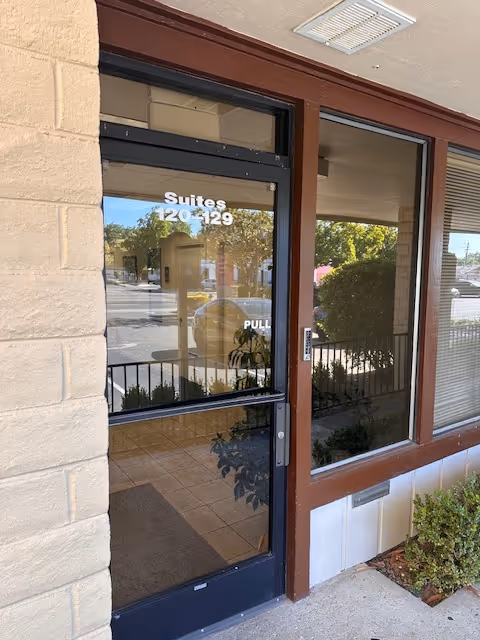 Exterior entrance to AM Aesthetics with glass door and suite numbers.