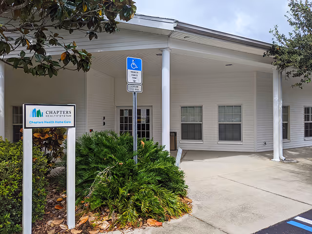 Exterior view of a Chapters Health Home Care building with handicap parking sign and greenery.