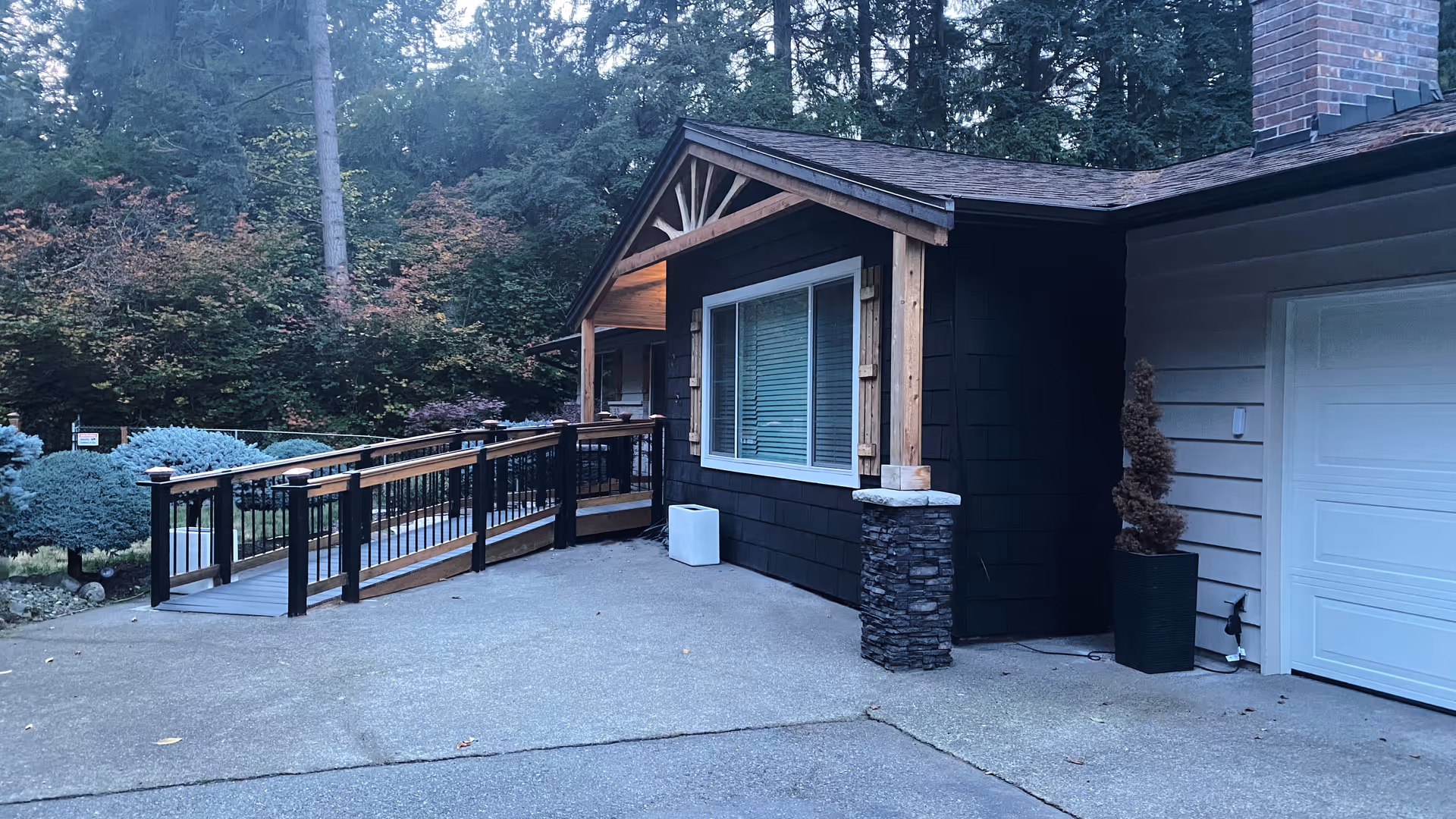 Exterior of a senior living facility with a ramp, porch, and landscaped surroundings.