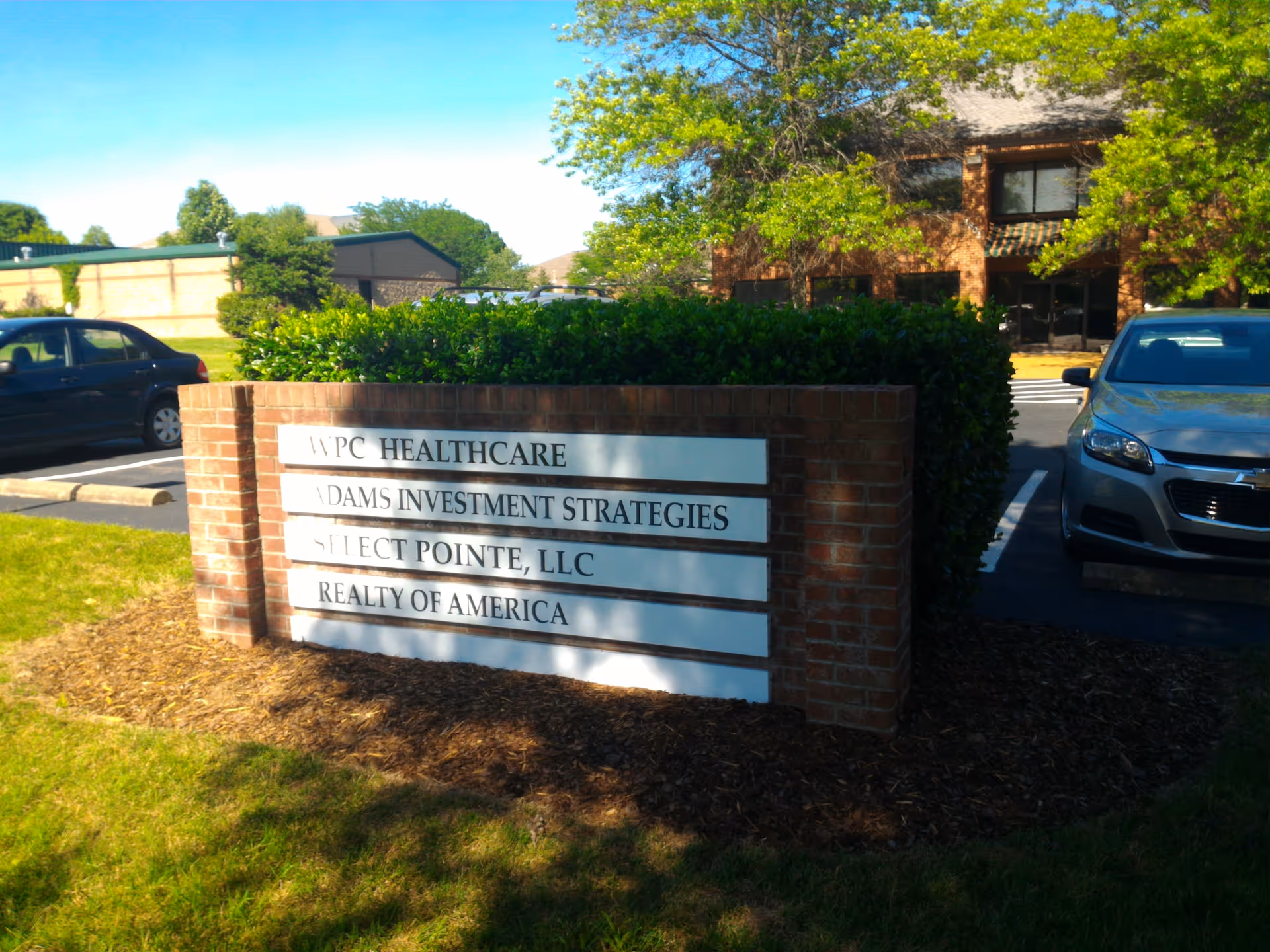 Brick sign with WPC Healthcare and partner names in front of a brick building.