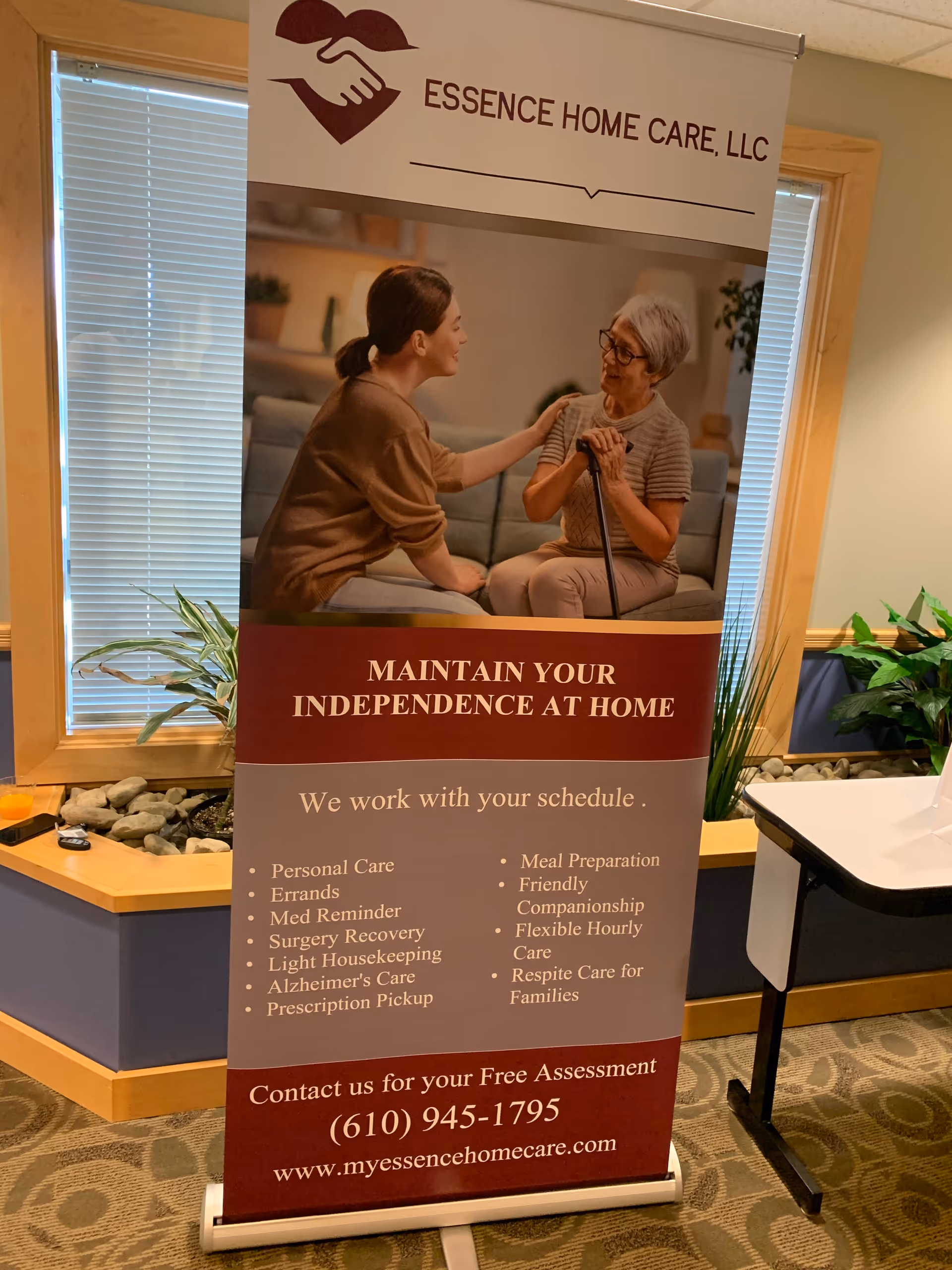 Indoor lobby with a freestanding Essence Home Care banner showing a caregiver and elderly woman.