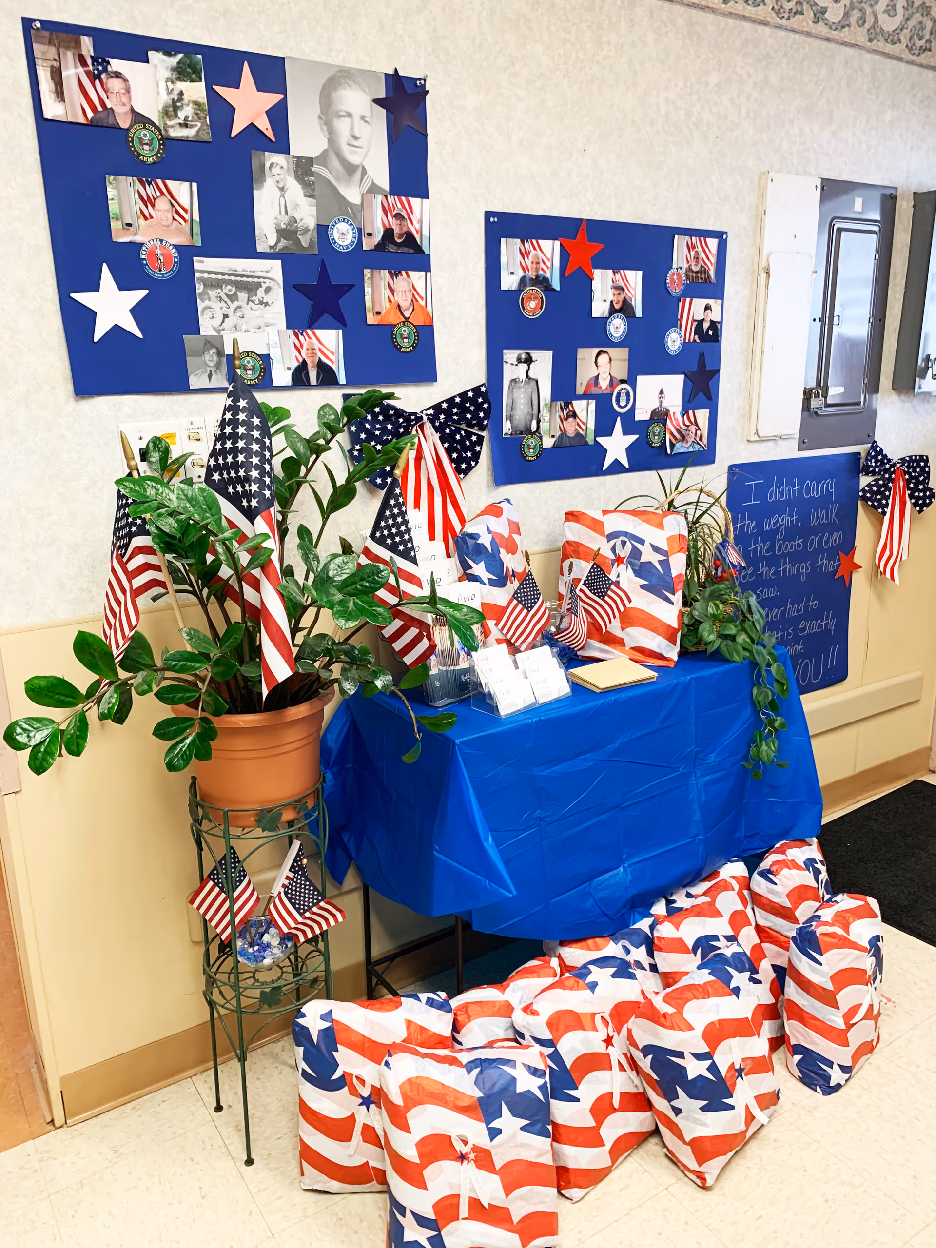 Patriotic display with flags, stars, photos, and a blue table in a hallway.