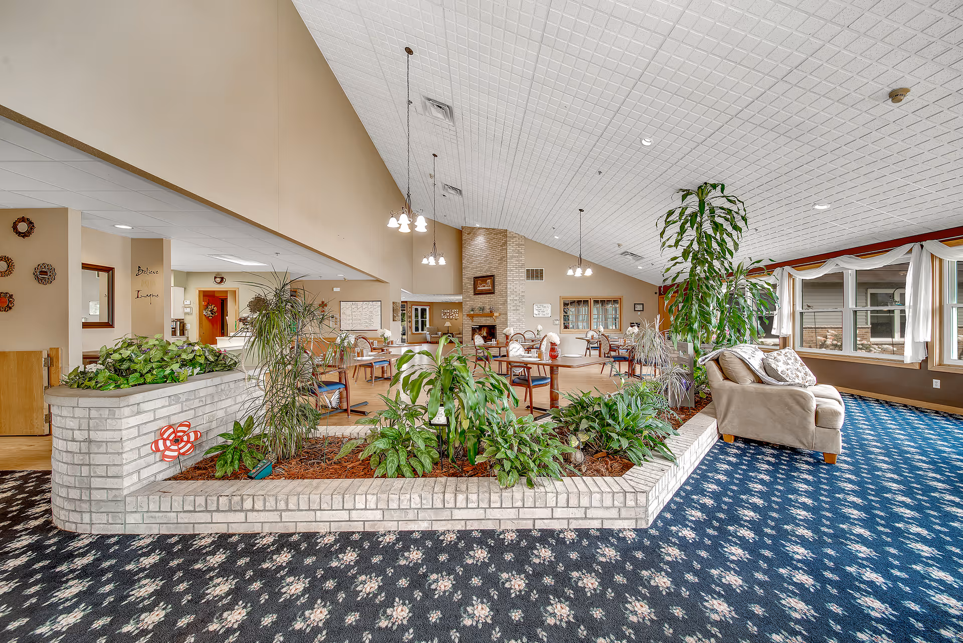Bright indoor lounge in a senior living facility with plants and seating.