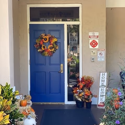 Blue front door with autumn wreath at Vista Lake entrance, surrounded by plants