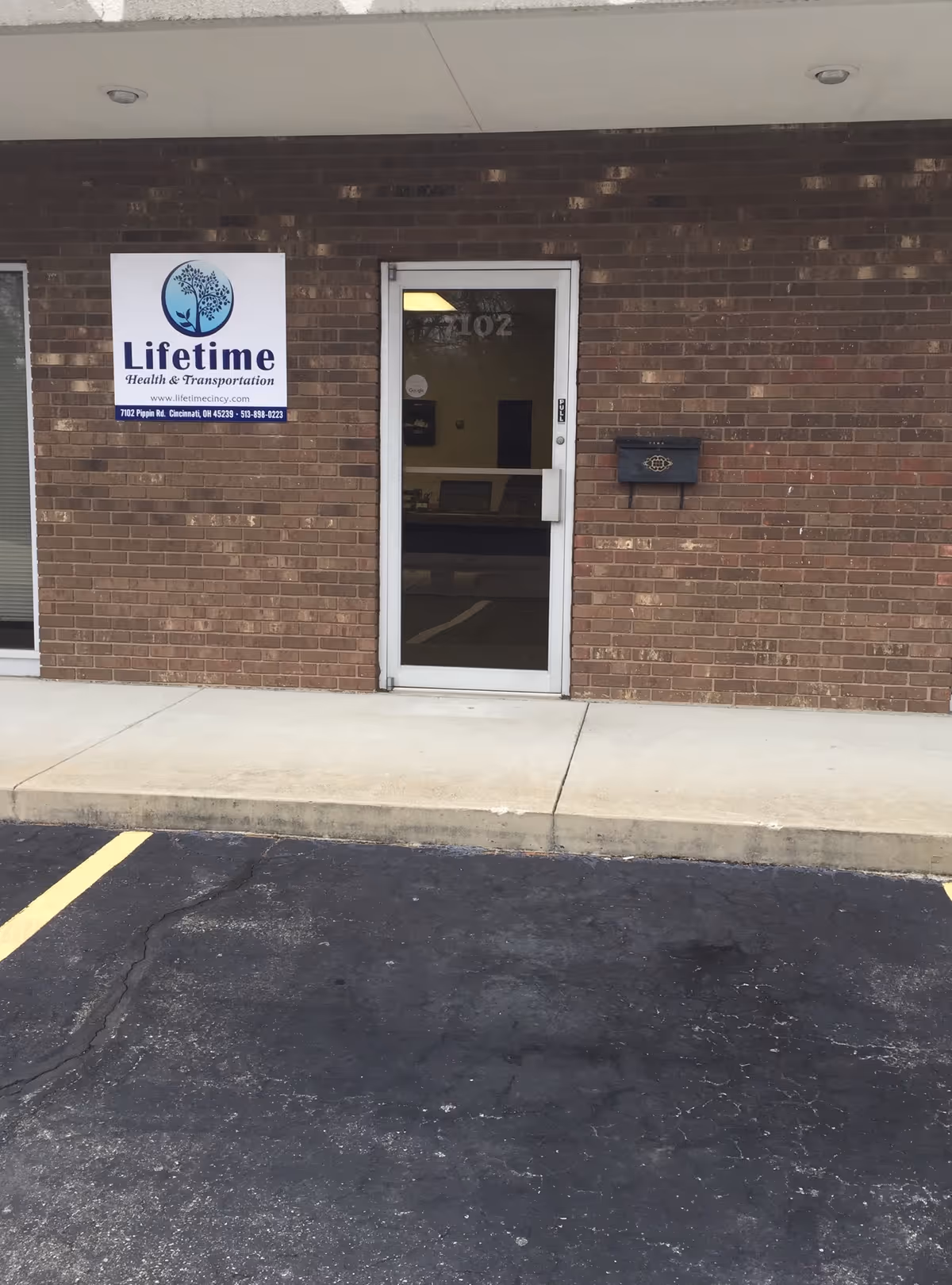 Brick facility entrance with Lifetime Health & Transportation sign and glass door.