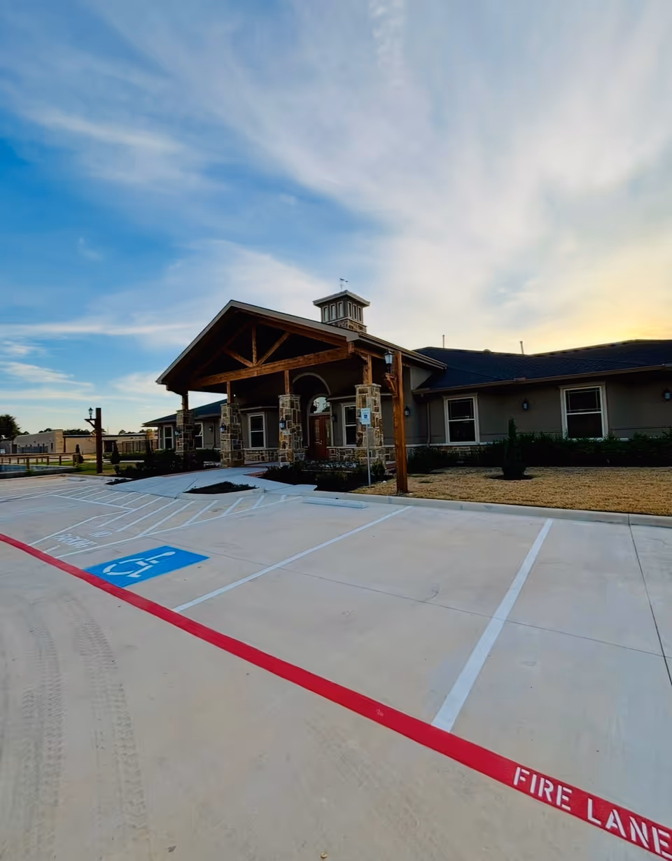 Exterior view of Village Green Alzheimer's Care Conroe facility entrance with handicap parking in foreground