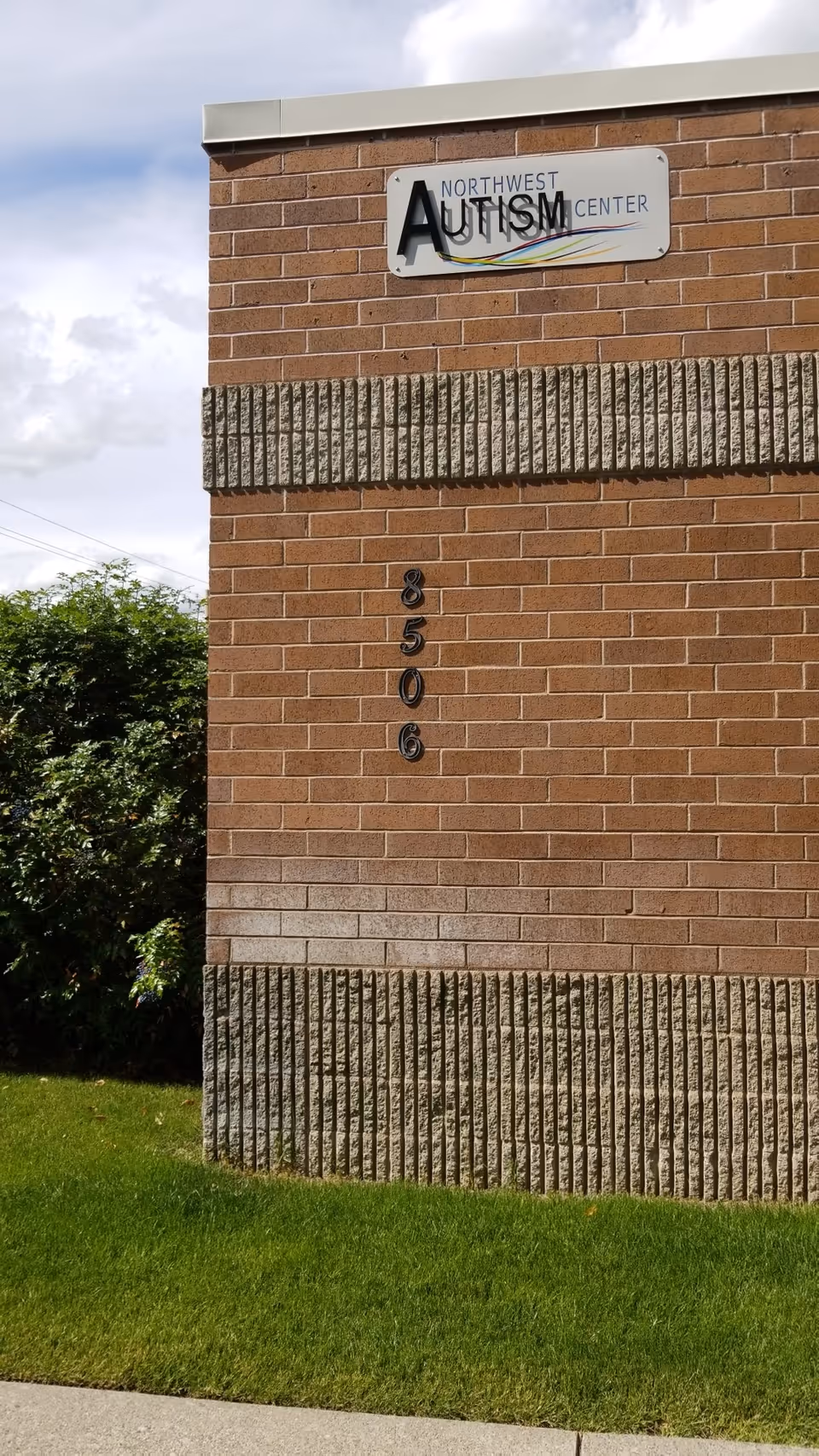 Exterior brick wall with Northwest Autism Center sign and vertical address numbers.