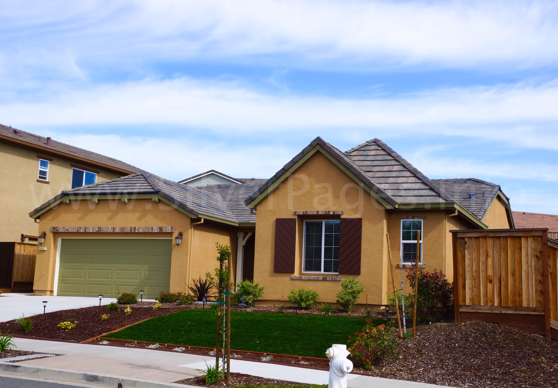 Harmony Care Home building front, tan exterior, two-car garage, and a tidy lawn.