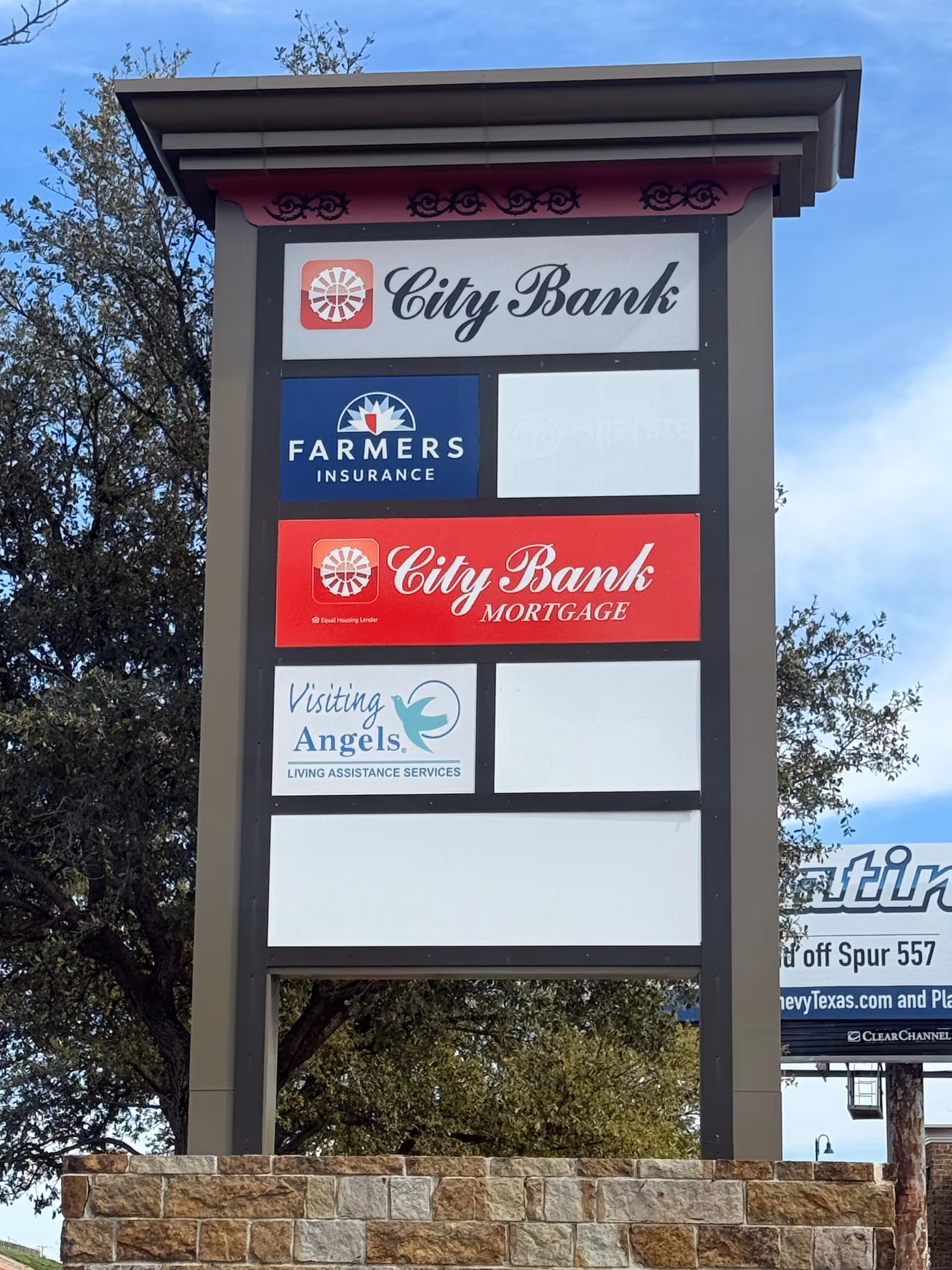 Outdoor signboard displaying City Bank, Farmers Insurance, City Bank Mortgage, and Visiting Angels logos.