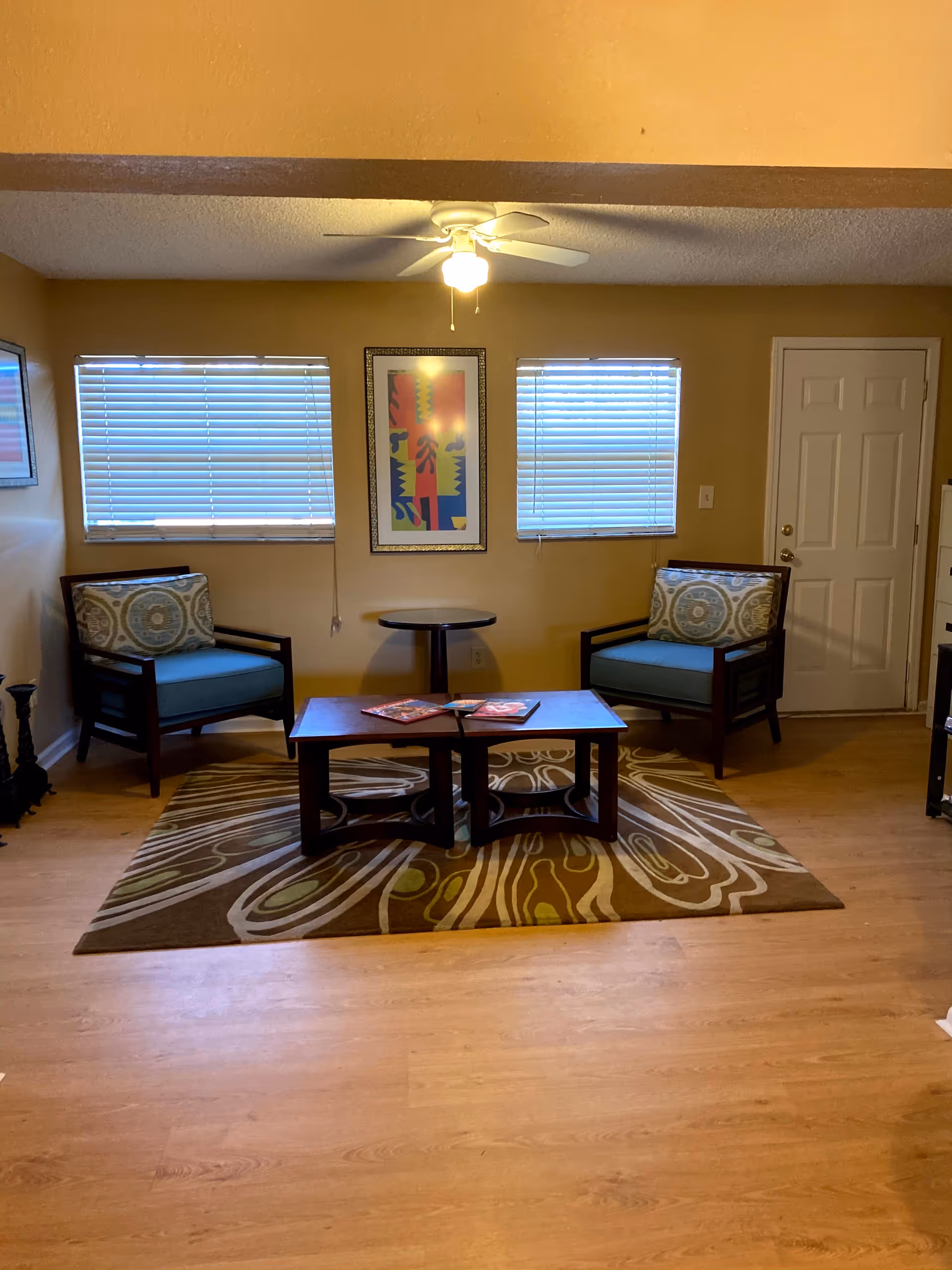 Two blue-cushioned chairs face a central coffee table in a cozy living room.