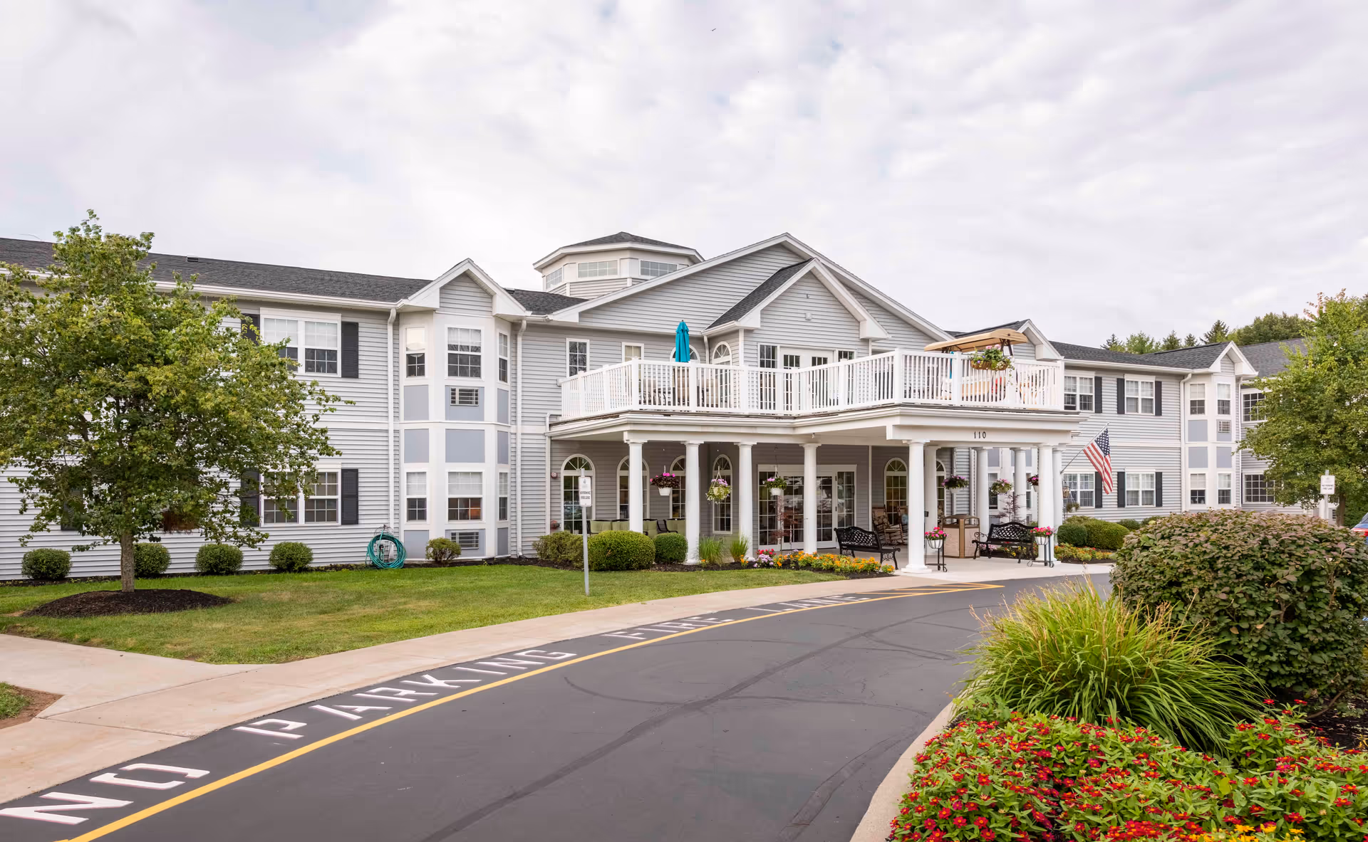 Exterior view of Seabury Woods with front entrance, balcony, and landscaped surroundings