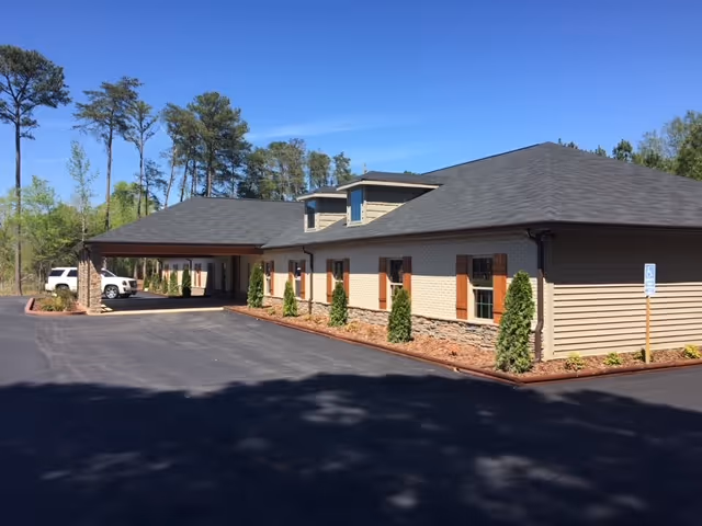 Exterior view of an assisted living facility with a covered entrance and parking.