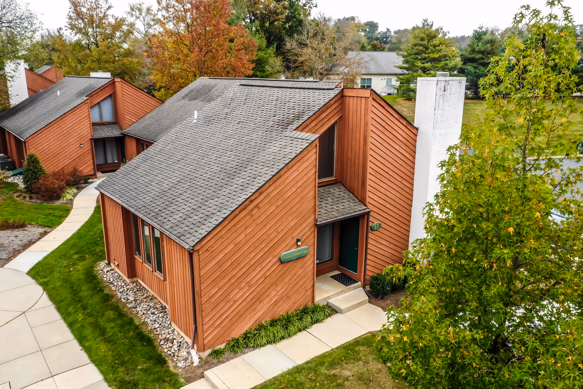 Exterior view of brown wooden senior living cottages with sloped gray roofs.