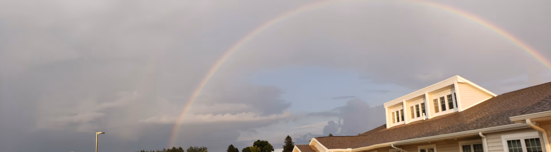 Front exterior of Wynwood House Personal Care Homes with a double rainbow.