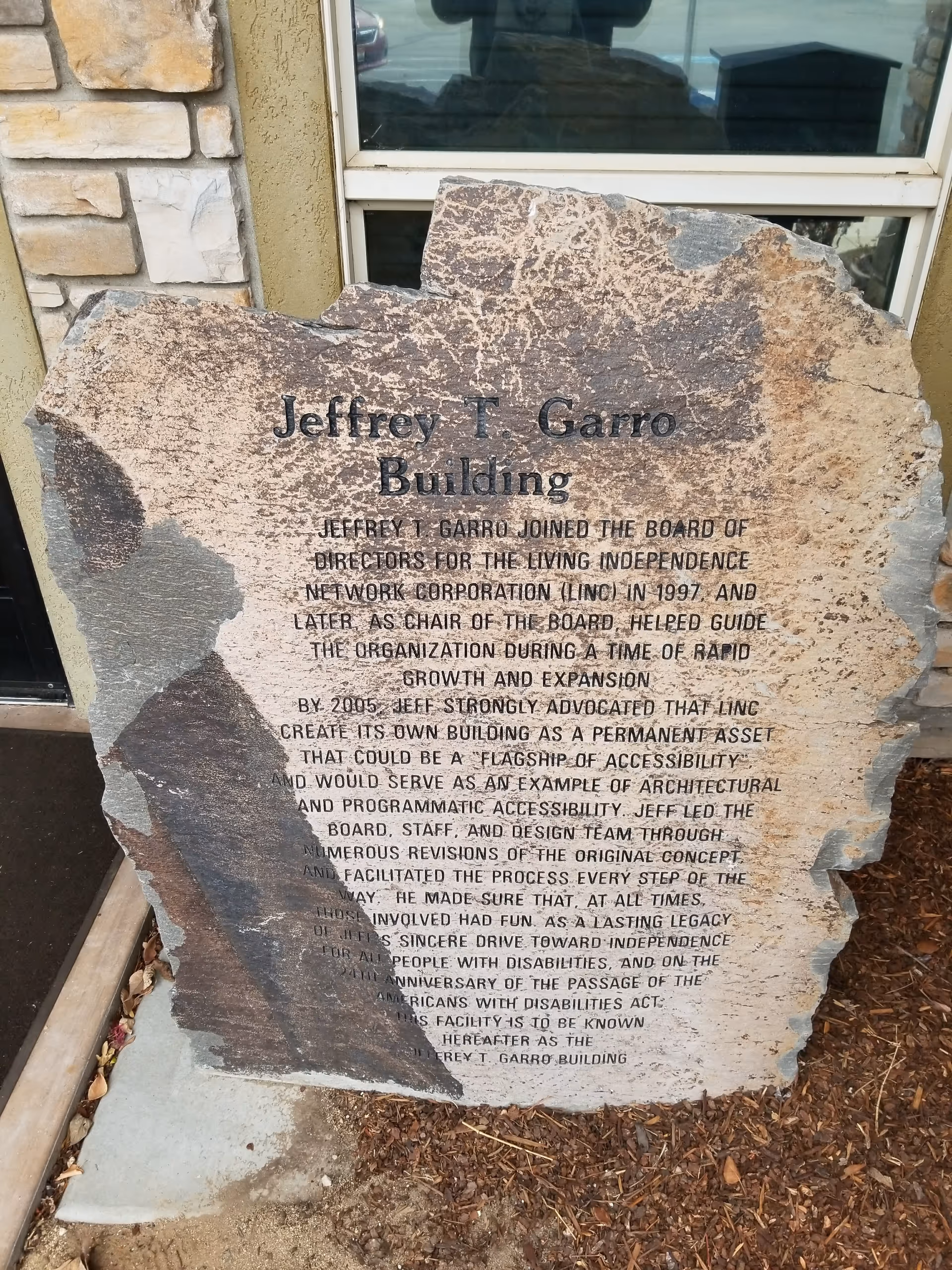 Weathered stone plaque near a building entrance, engraved with Jeffrey T. Garro Building text.