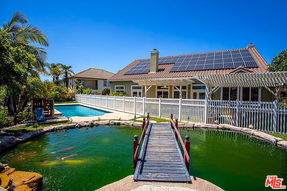 Exterior view of a senior living facility with a bridge over a pond and pool