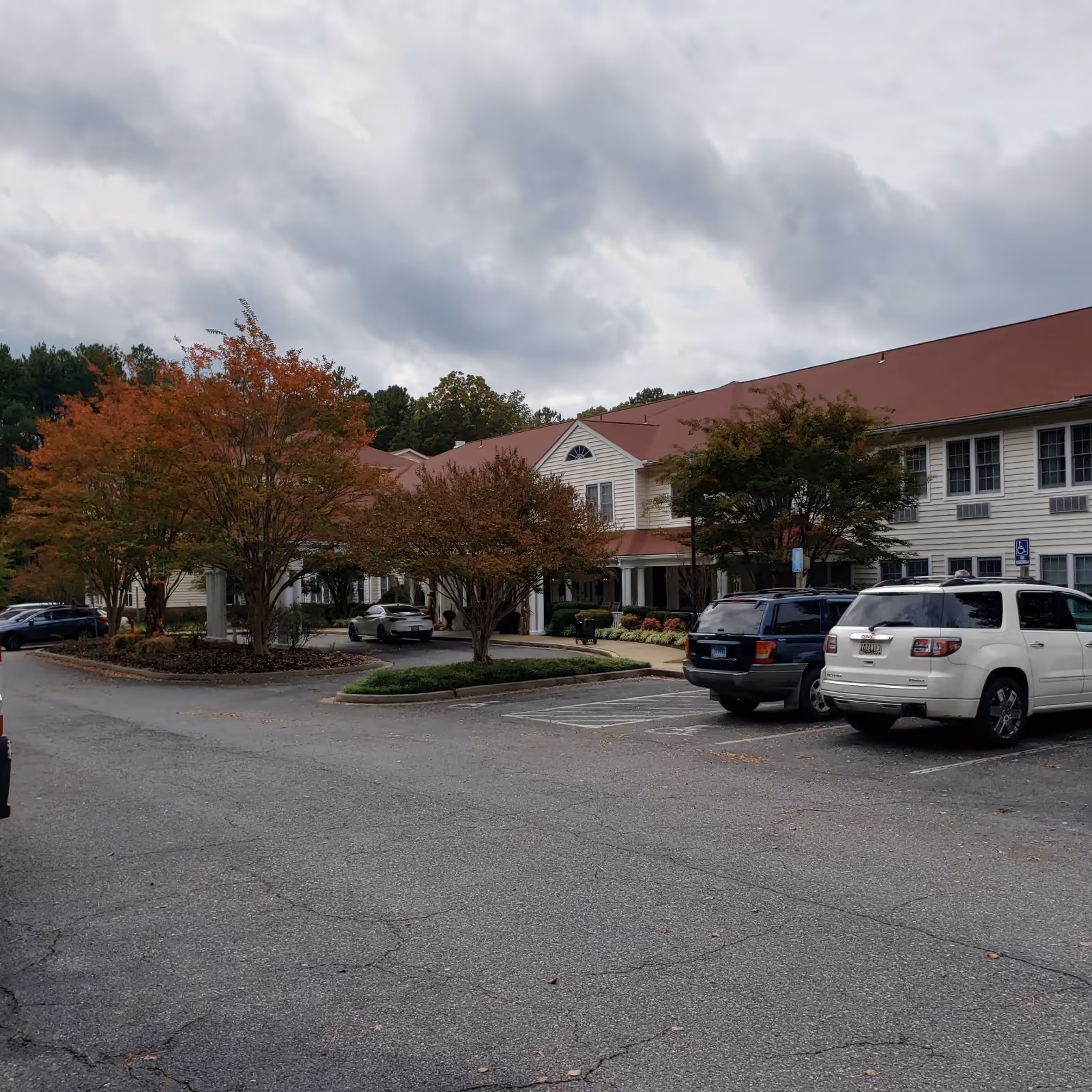 Exterior view of Hermitage at St. John's Creek with parked cars and trees.