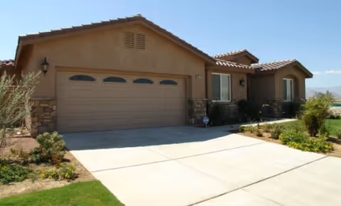 Desert Cottage II senior living facility exterior shows a tan stucco house with a two-car garage.
