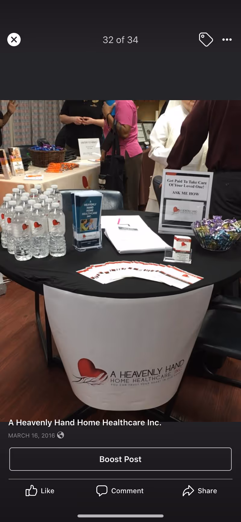 Promotional booth for A Heavenly Hand Home Healthcare with brochures, water bottles, and attendees nearby.