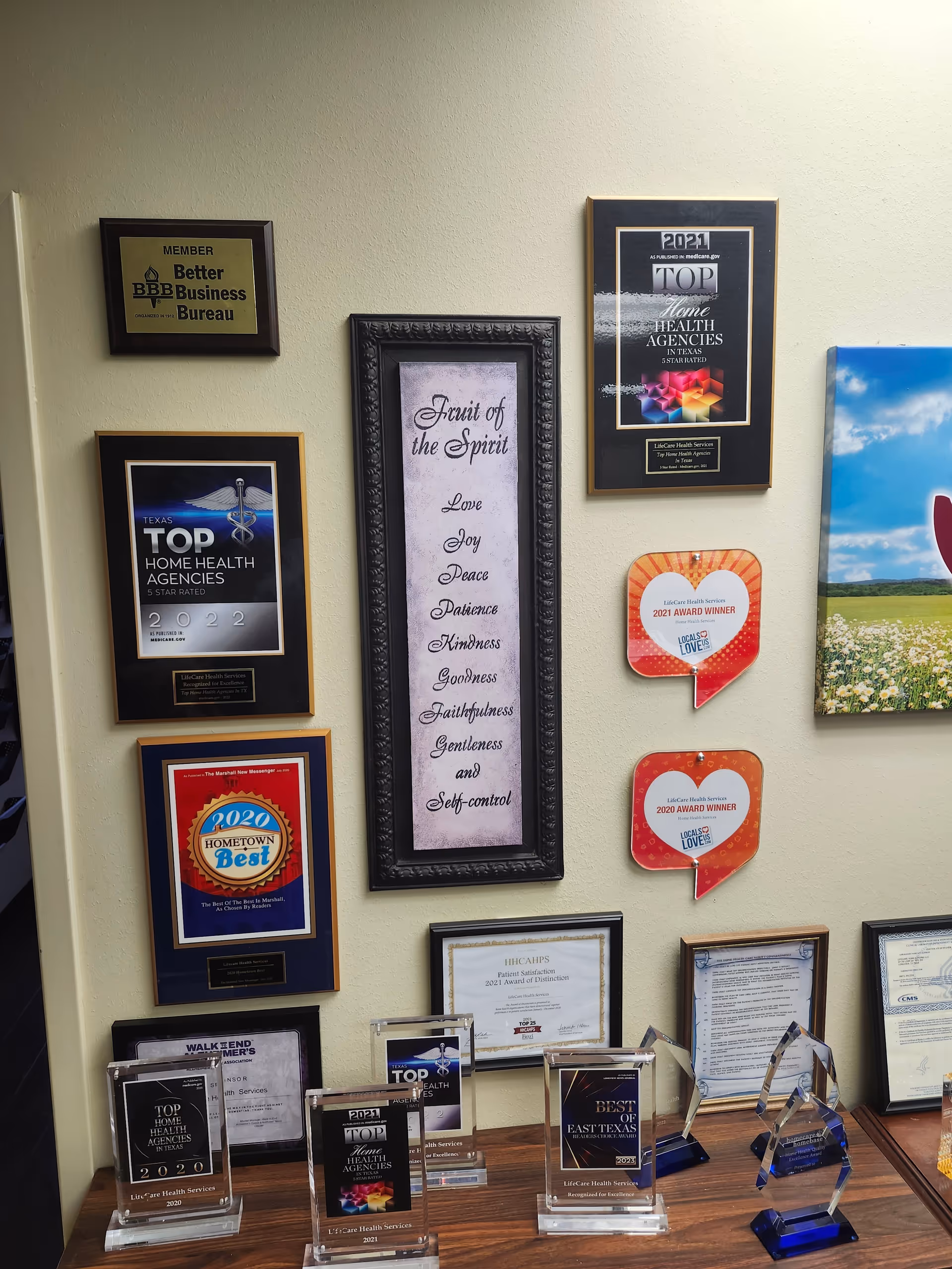 Wall display of framed awards and certifications in a senior living facility lobby.