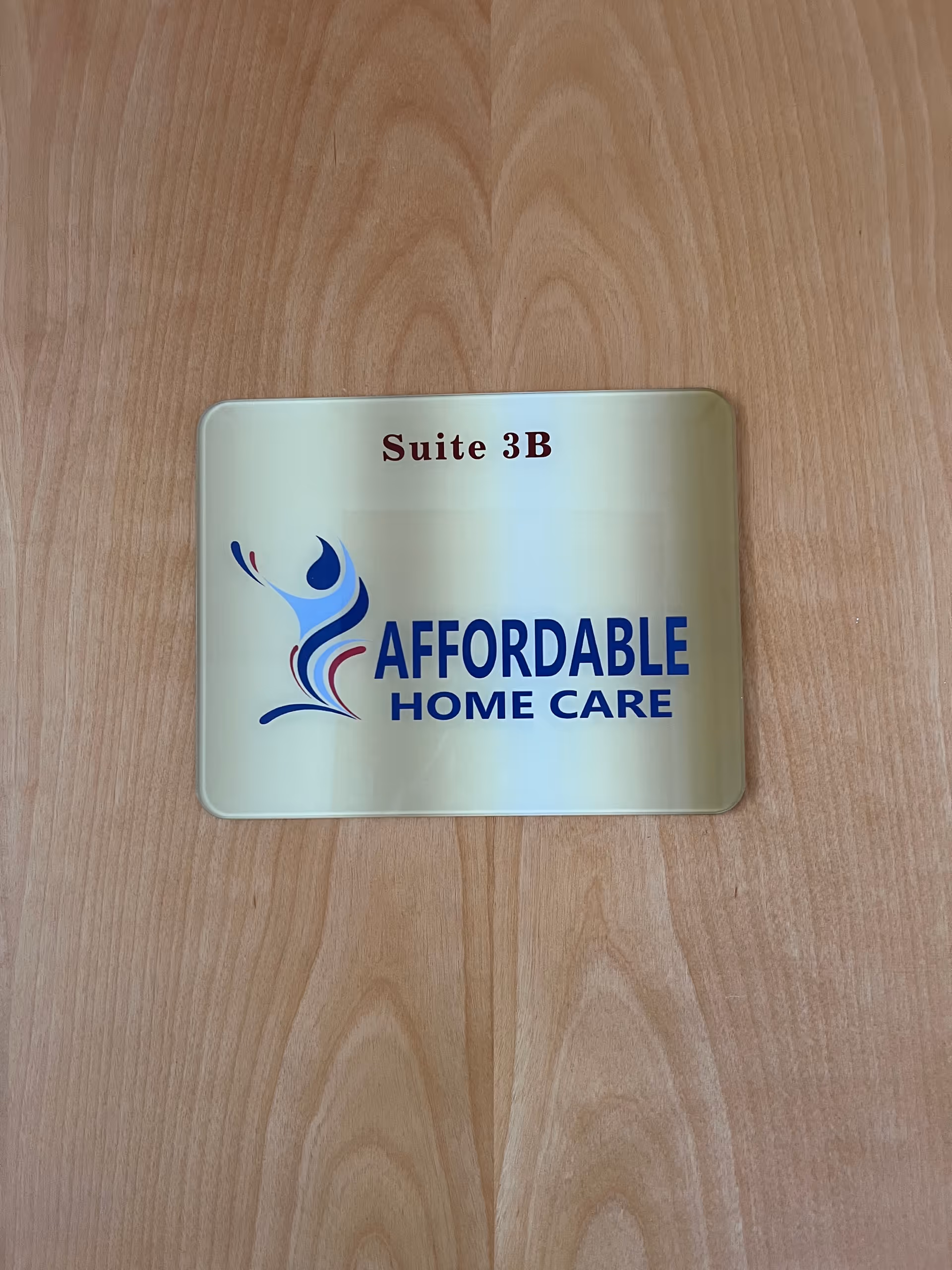 Metal sign on a wooden floor displaying Suite 3B and Affordable Home Care.