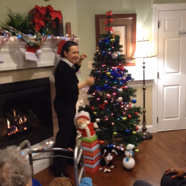 A person dances beside a decorated Christmas tree in a cozy living room.
