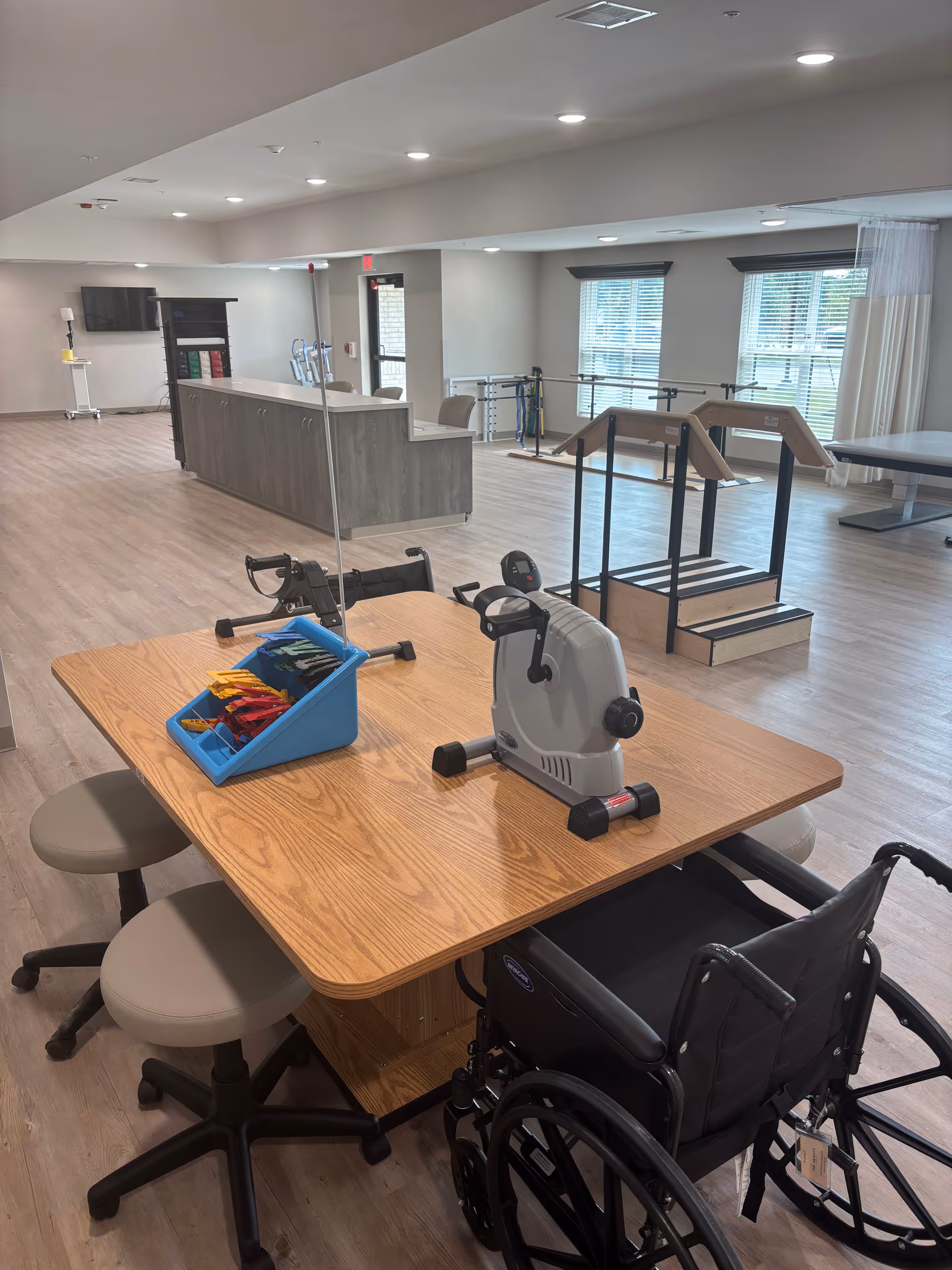 Inside a senior living facility, a rehab room with a table, equipment, and wheelchair.