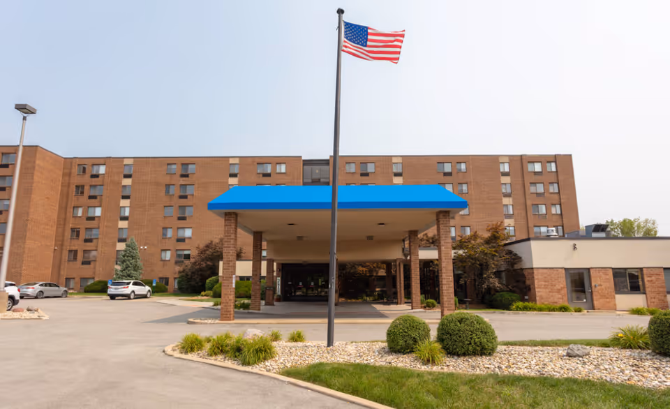 Exterior view of Saxony Court Senior Living with brick building and blue entrance canopy.
