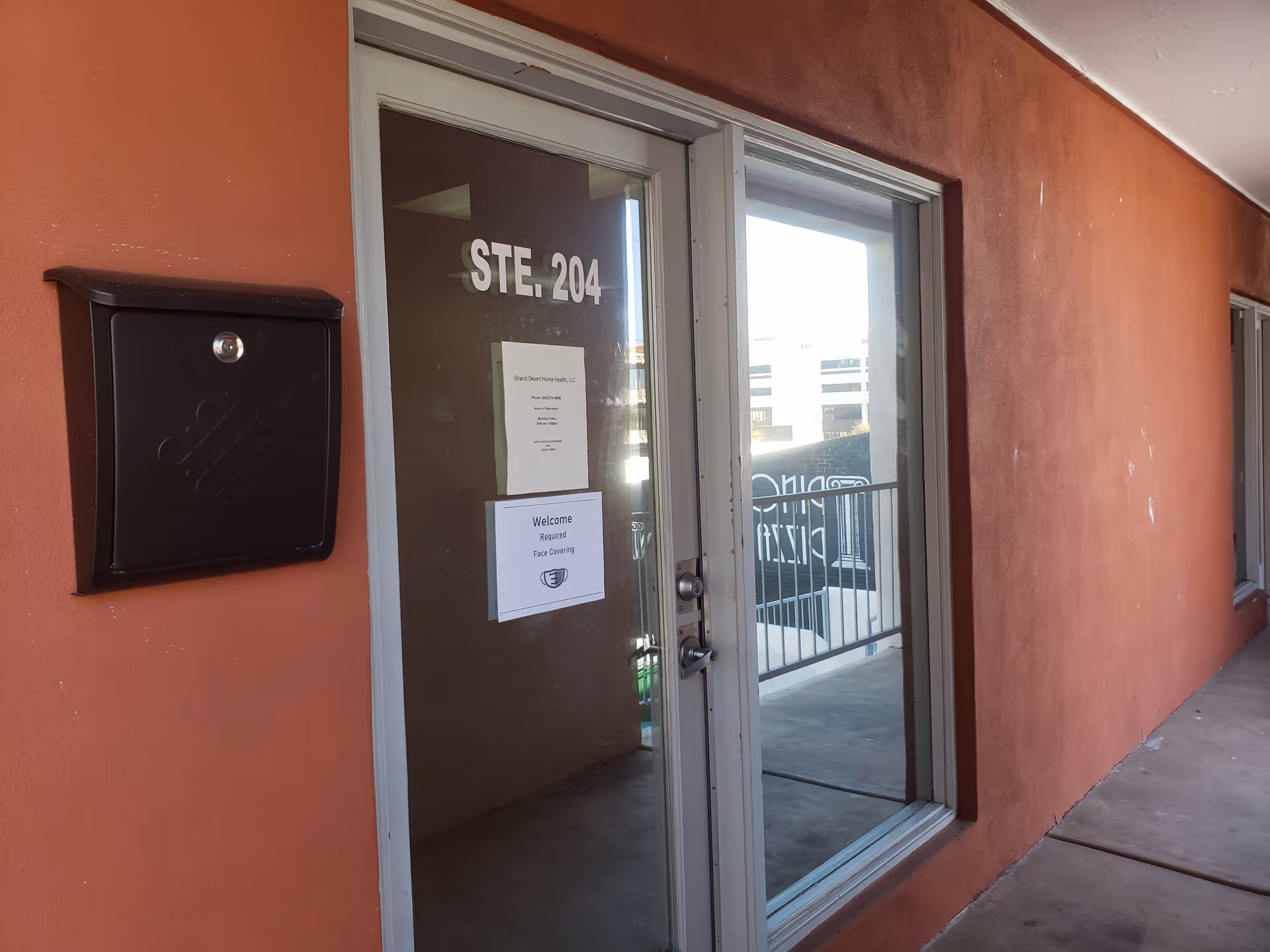 Orange exterior wall with glass door labeled STE. 204 and a mailbox