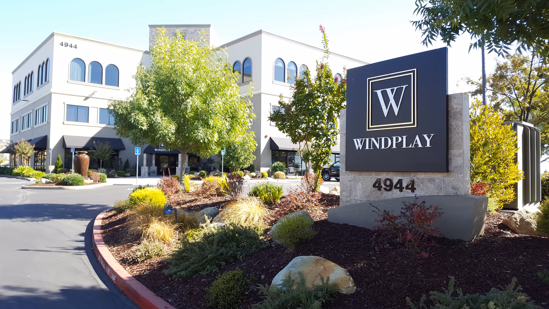 Exterior view of a modern senior living facility with a Windplay sign and landscaped entrance.