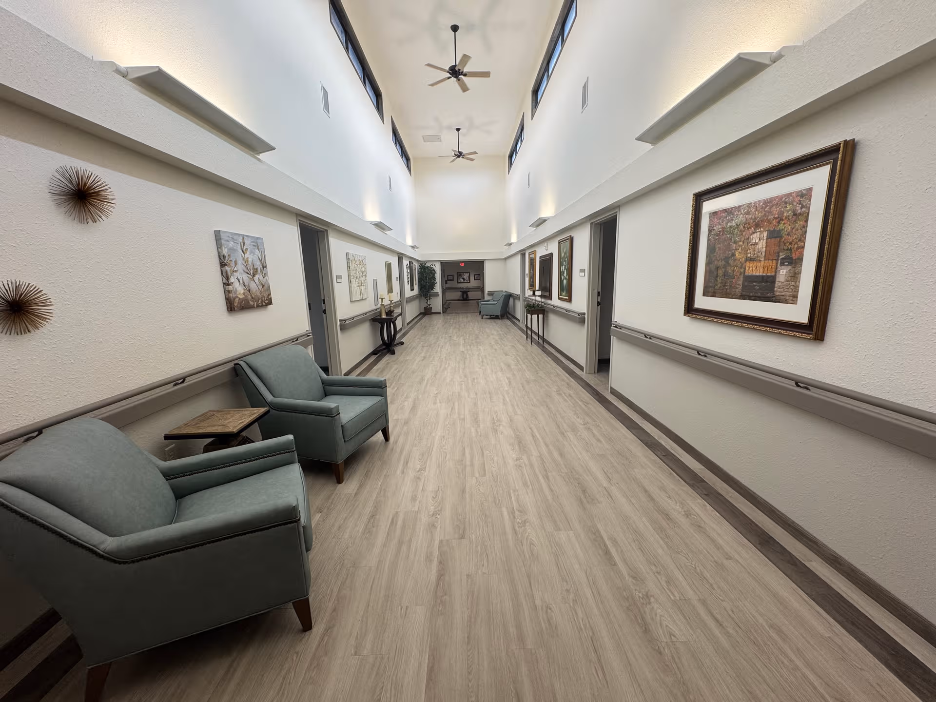 Long, well-lit hallway at Brown Wilcox Retirement Home with seating and framed artwork along walls.