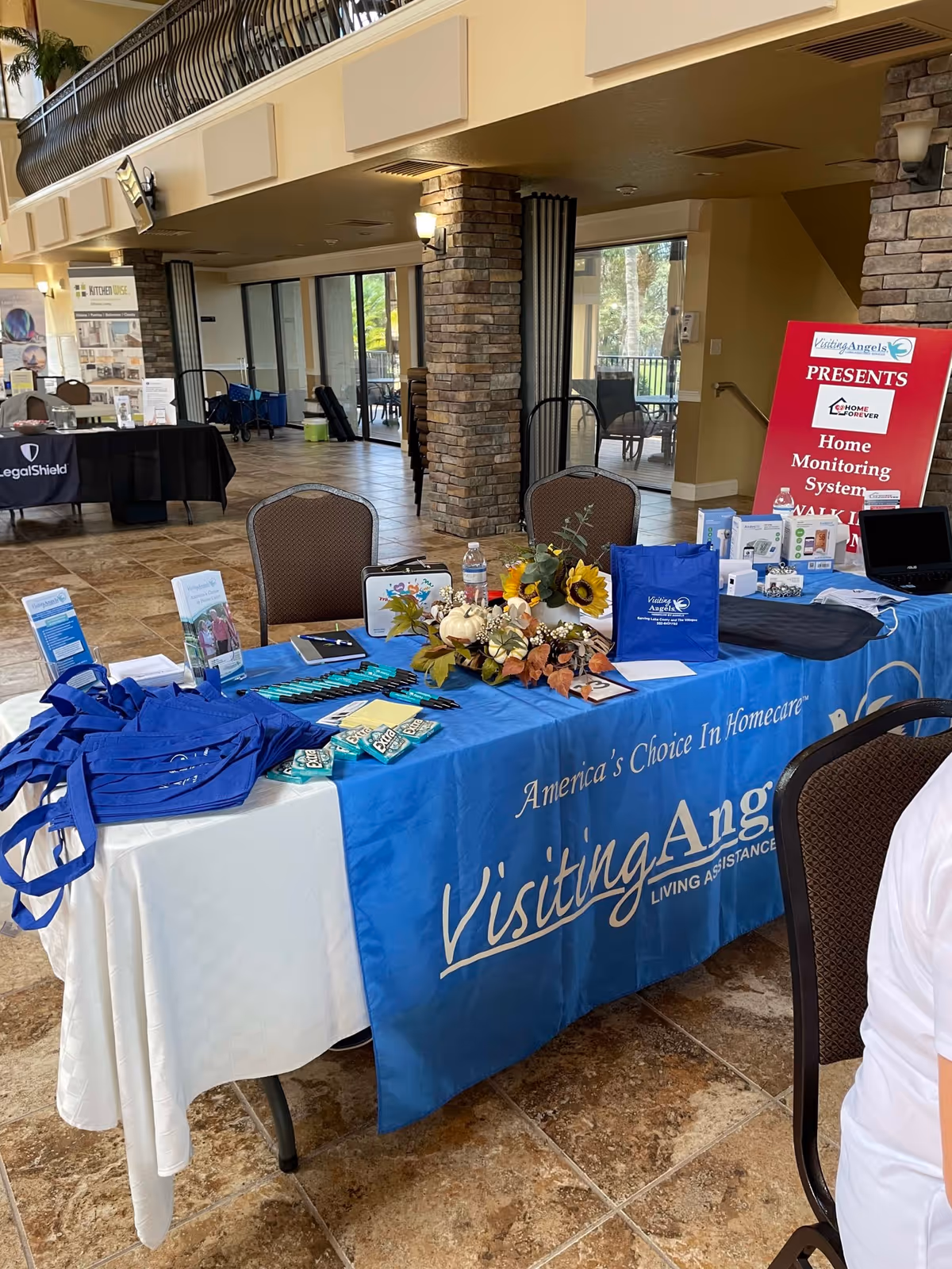Lobby area featuring a blue Visiting Angels information table and promotional displays.