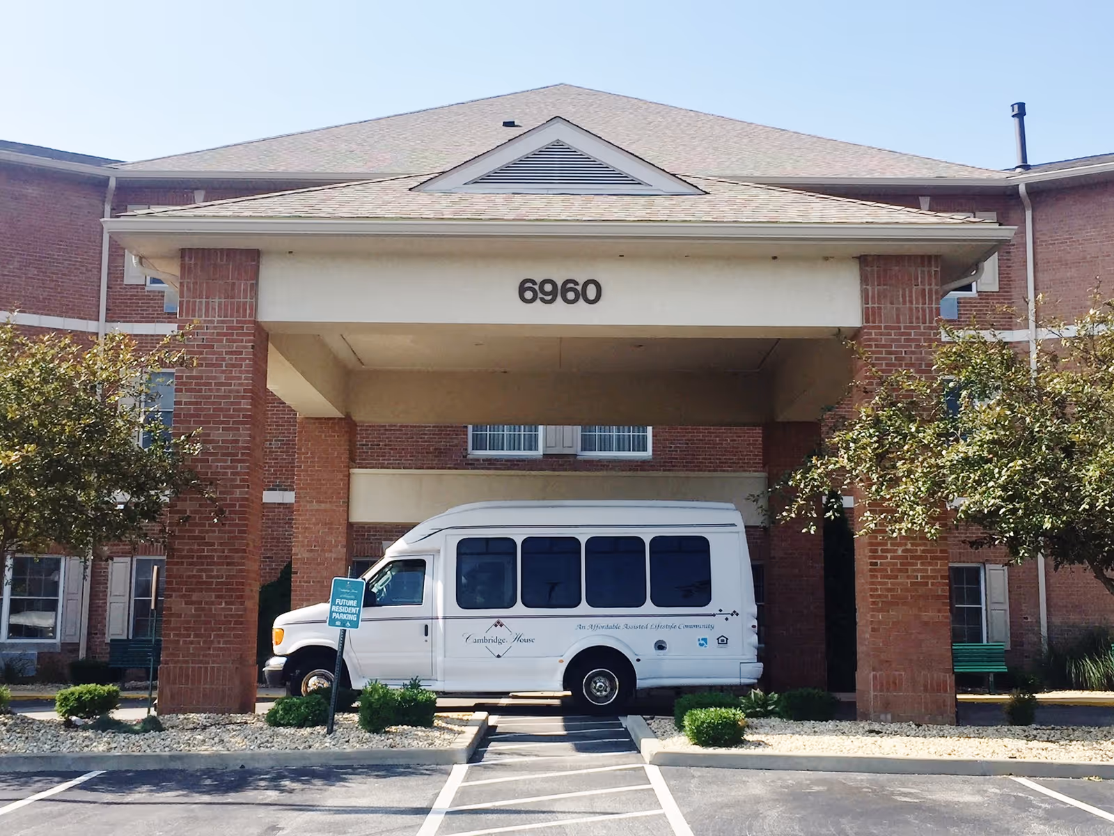 Front view of Cambridge House entrance with a shuttle bus parked under the covered drop-off.
