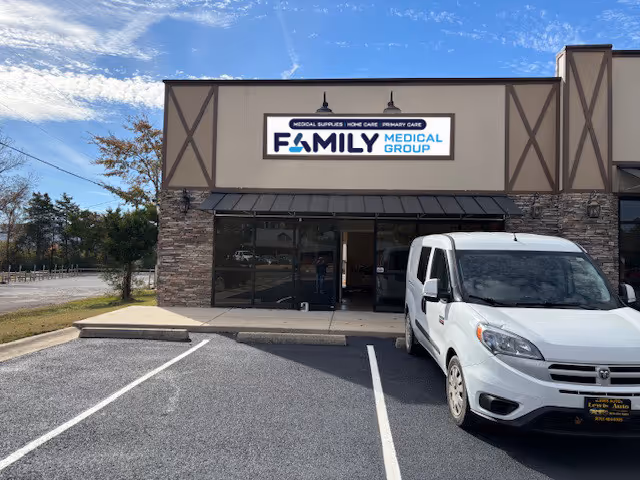 Front view of a medical facility with a white van parked in the lot.