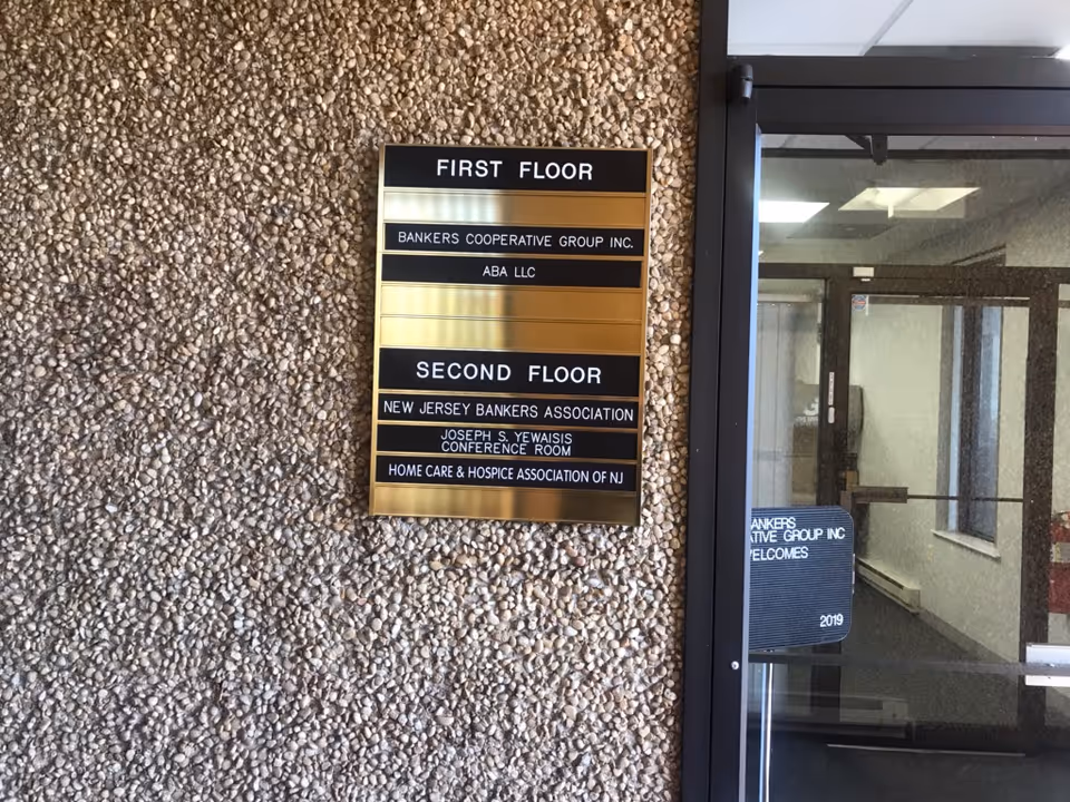 Exterior pebbled wall features a floor directory sign beside the building entrance.