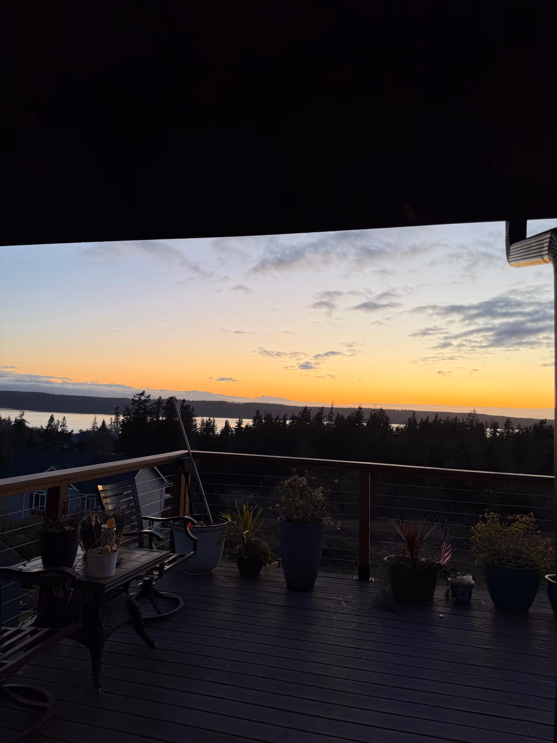 Sunset over water seen from Crest View balcony with potted plants.