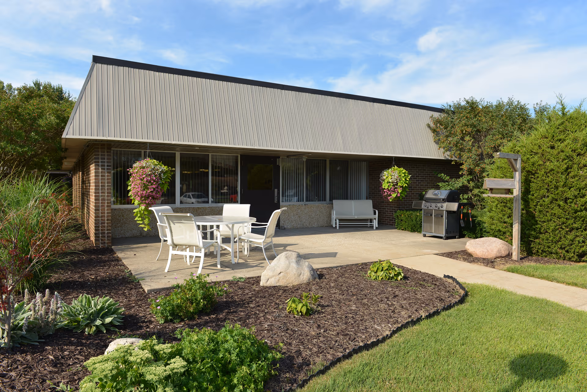 Exterior view of Maplewood of Sandy Creek with patio seating and landscaped front yard.