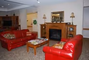 Red leather couches surround a wooden coffee table in a cozy living room with fireplace.