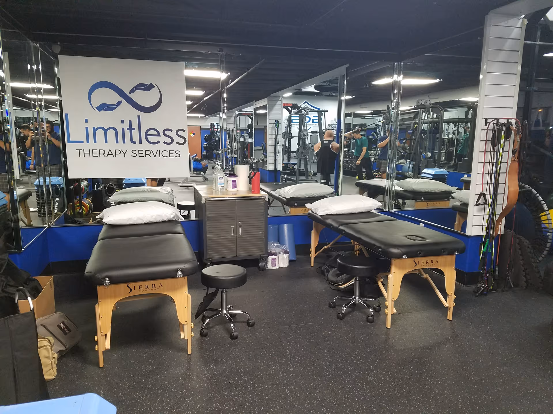 Interior therapy gym with treatment tables, mirrors, and various exercise equipment.