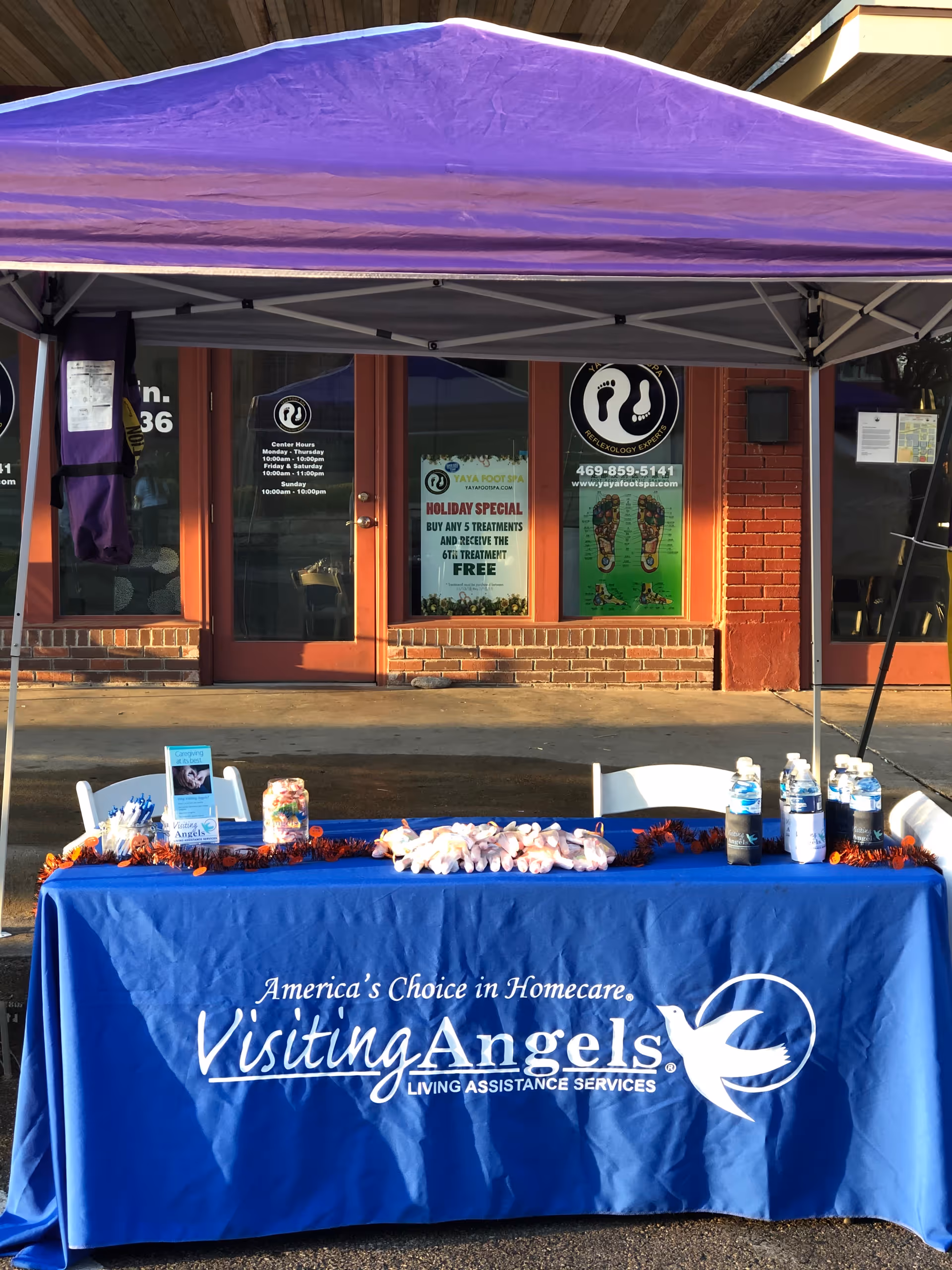 Outdoor booth with a blue Visiting Angels table under a purple canopy.