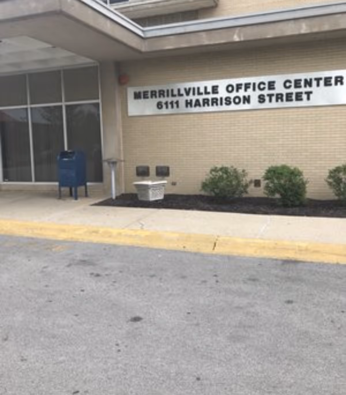 Exterior view of a beige office building with a sign reading Merrillville Office Center.