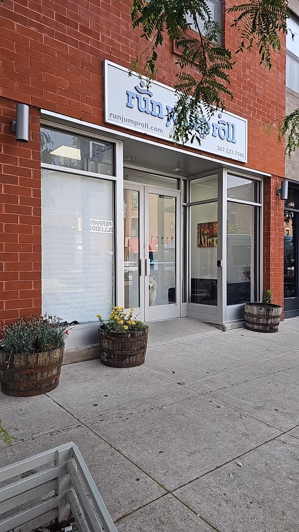 Brick storefront with glass doors and planters outside the entrance.