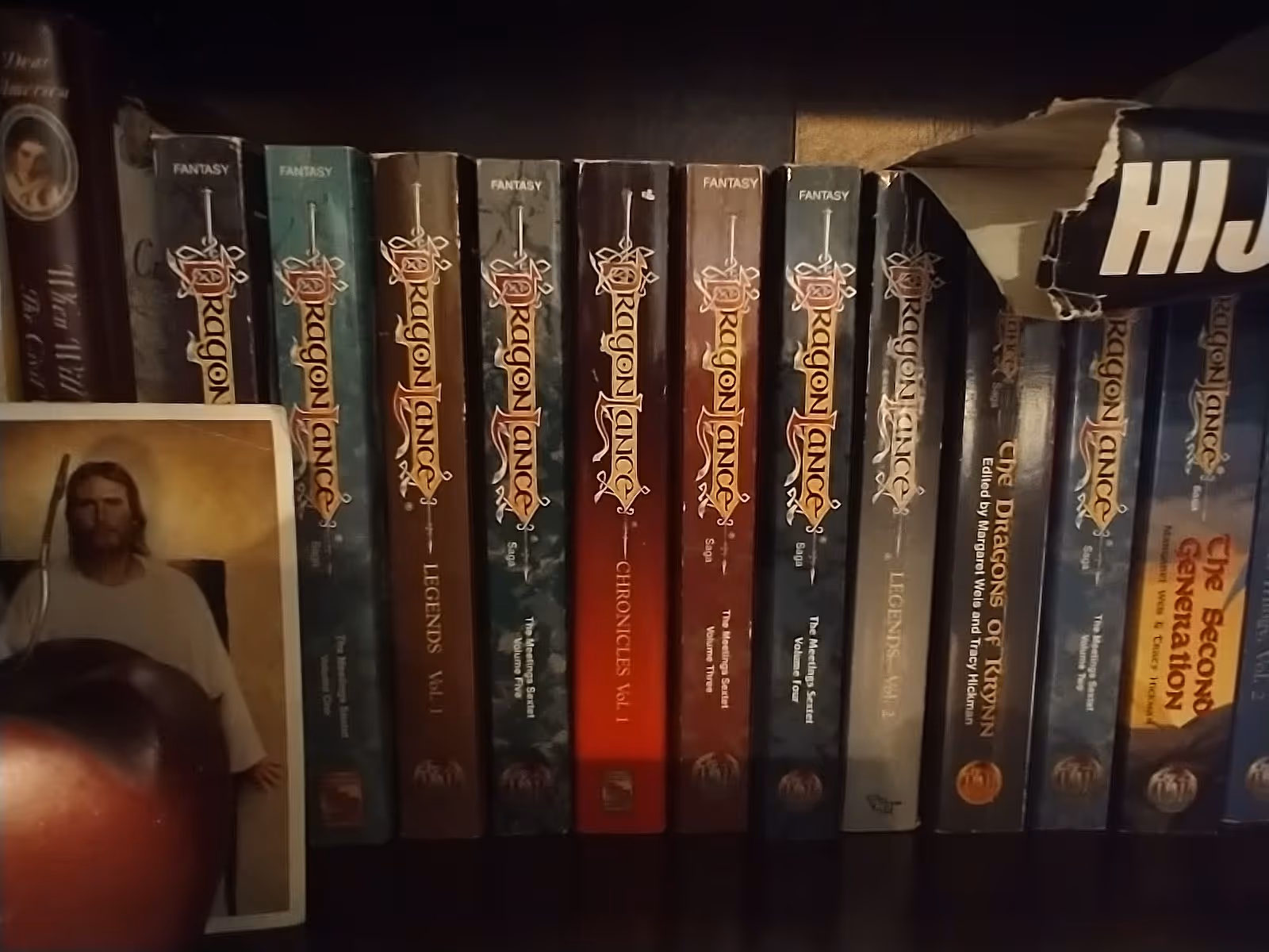 Shelf of Dragonlance fantasy books on a dark wood bookcase inside Country Oaks Assisted Living.