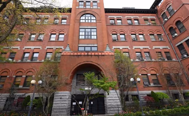 Exterior view of Cobble Hill Health Center: red brick building with arched windows and gated entrance.