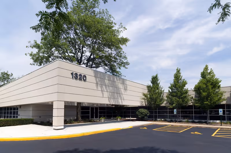 Exterior view of a single-story building with 1320 address, parking, and trees.