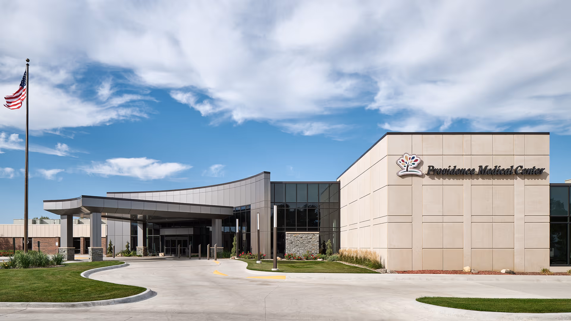Exterior view of Providence Medical Center building with flagpole and curved entrance.