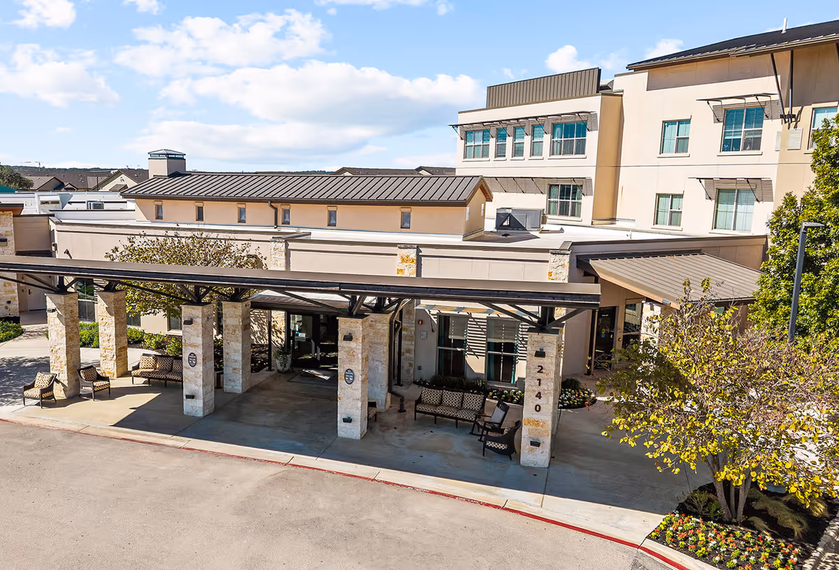 Exterior of Élan Westpointe at New Braunfels; entrance with canopy, stone pillars, and seating.