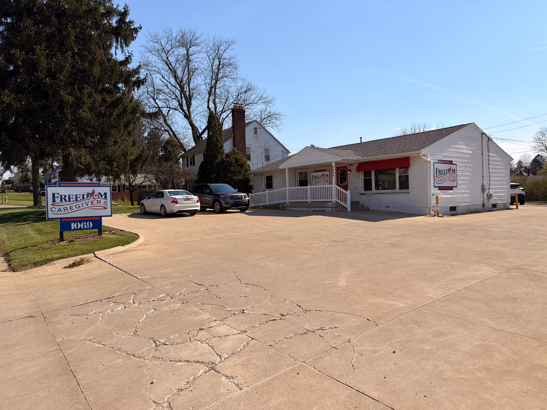 White single-story building with a red awning, parking lot, and Freedom Caregivers Mansfield sign